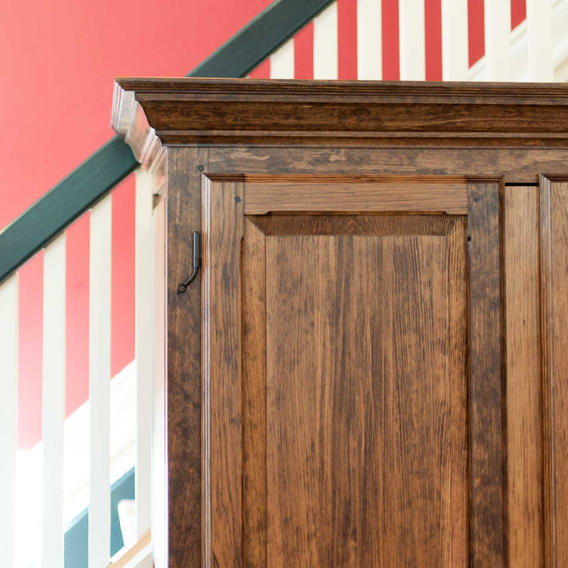 Solid wood raised panel armoire in provincial, angle on, top corner and crown moulding detail