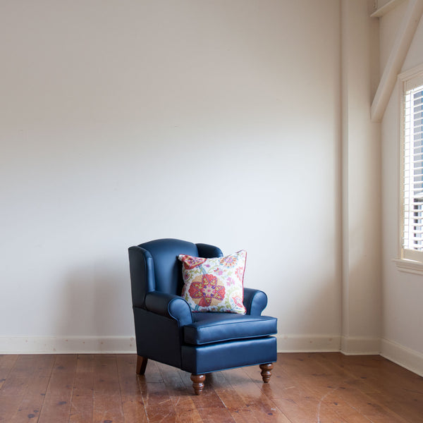Walmer wingback chair in navy leather with contrasting toss pillow, wide crop, angle view